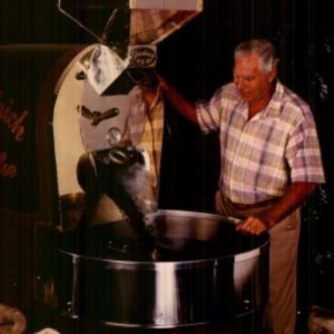Photo of a man pouring roasted coffee beans out of a coffee roaster